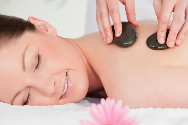 Young woman closing her eyes while having a hot stone massage — Stock Photo, Image