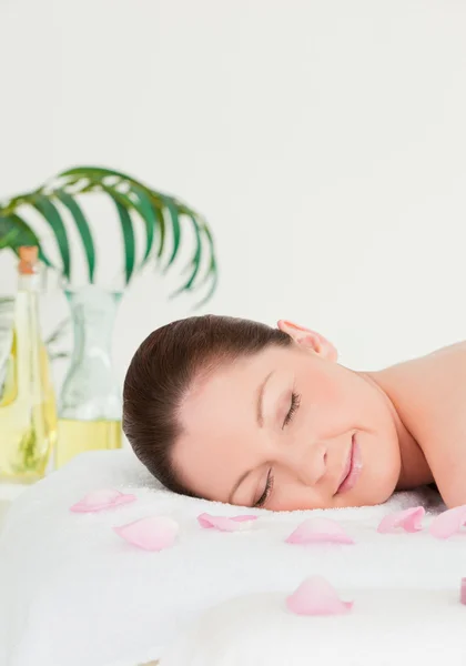Retrato de uma jovem deitada em uma mesa de massagem com pétalas — Fotografia de Stock