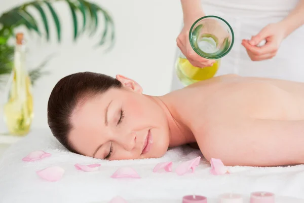 Massaggiatrice versing olio da massaggio sulla schiena di una bella donna in uno sp — Foto Stock