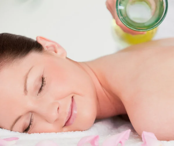 Sorridente giovane donna avendo massaggio olio versed su il suo indietro — Foto Stock