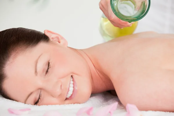 Massagista colocando óleo de massagem nas costas de uma mulher bonita — Fotografia de Stock