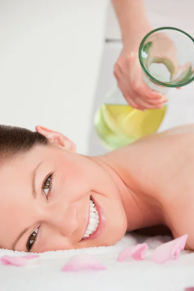 Ritratto su una donna sorridente con olio da massaggio versato sul suo bac — Foto Stock