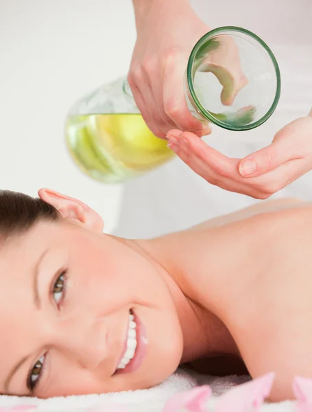 Portrait of a smilling woman getting massage oil on her back in — Stock Photo, Image