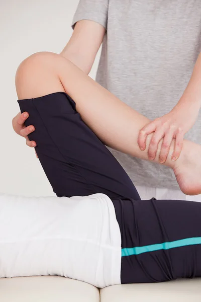 Retrato de uma massagista esticando a perna de uma mulher youn — Fotografia de Stock
