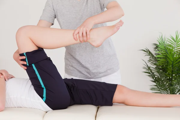 Massagista esticando a perna direita de uma jovem — Fotografia de Stock
