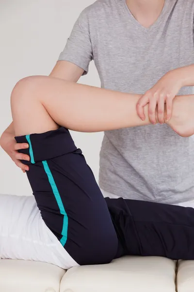 Portrait of a masseuse stretching the right leg of an athletic w — Stock Photo, Image