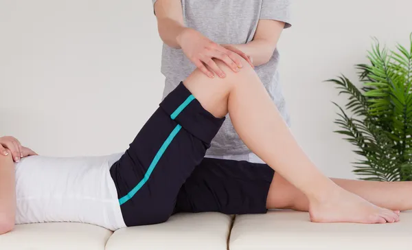 Masseuse massing the knee of an athletic woman — Stock Photo, Image