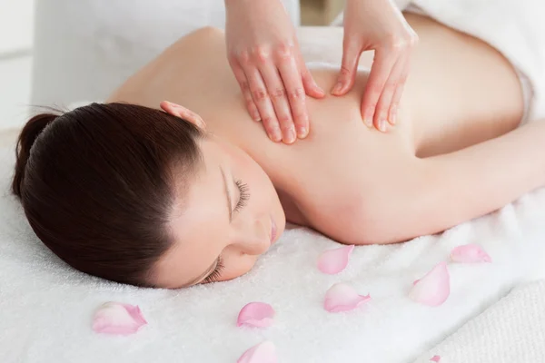 Mulher bonita tendo uma massagem nas costas cercada por pétalas — Fotografia de Stock
