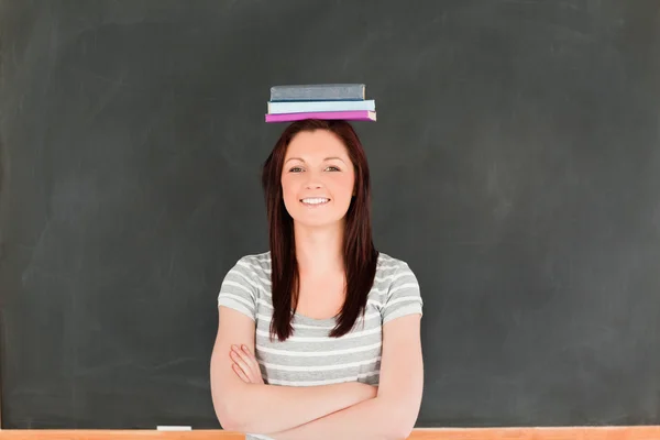 Smilling söt kvinna som bär böcker på hennes huvud — Stockfoto