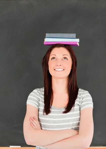 Porträtt av en smilling söt kvinna balansera böcker på hennes huvud — Stockfoto