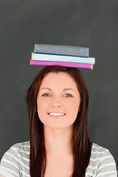 Retrato de uma jovem sorrindo usando livros na cabeça — Fotografia de Stock