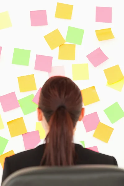 Redhead woman looking at a wall full of repositional notes — Stock Photo, Image