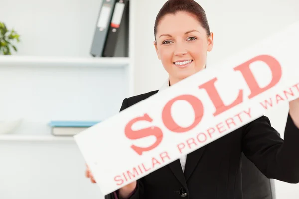 Hermoso agente de bienes raíces con un cartel vendido — Foto de Stock