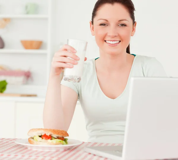 Donna attraente rilassante sul suo computer portatile e posa mentre beve — Foto Stock