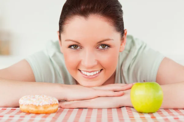 Schöne Frau posiert mit einem Donut und einem grünen Apfel — Stockfoto