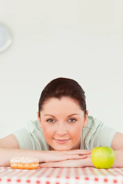 Pretty woman posing with a donut and a green apple — Stock Photo, Image