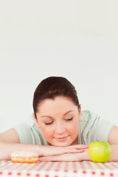 Charming woman posing with a donut and a green apple — Stock Photo, Image