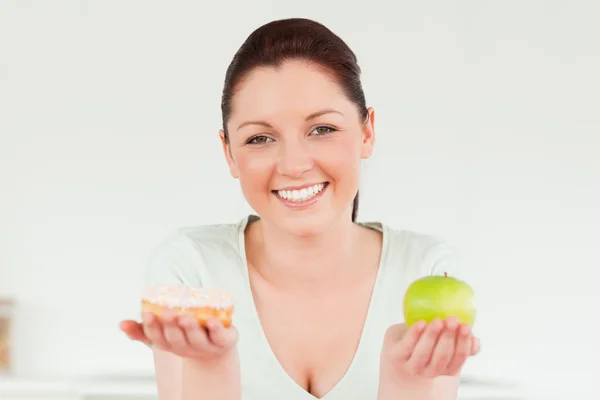Goed ogende vrouw poseren terwijl een donut en een groene appl — Stockfoto