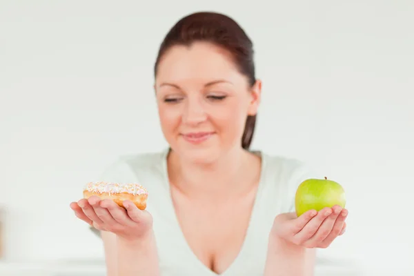 Donna attraente posa mentre tiene una ciambella e una mela verde — Foto Stock