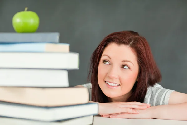 Giovane studentessa che guarda la mela in cima ai suoi libri — Foto Stock
