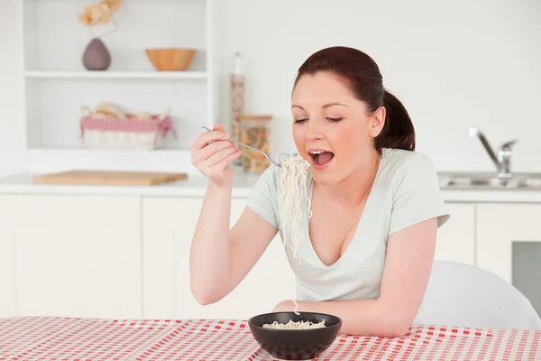 Goed ogende vrouw die zich voordeed tijdens het eten van een kom pasta — Stockfoto