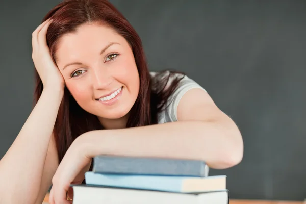 Крупным планом улыбается молодая студентка с предплечьем на книге — стоковое фото