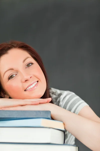 Portret uśmiechający się młoda kobieta, opierając się na jej książki — Zdjęcie stockowe