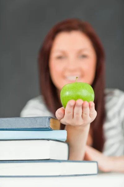 Retrato de um belo estudante mostrando uma maçã — Fotografia de Stock
