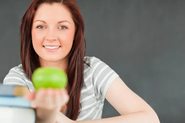 Beautilful young woman showing an apple with the camera focus on — Stock Photo, Image