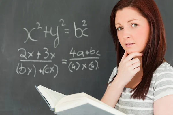 Mulher jovem reflexiva tentando resolver uma equação — Fotografia de Stock