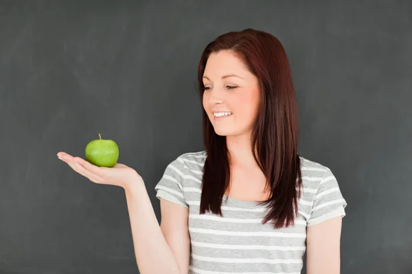 Jovem mulher olhando para a maçã na palma da mão — Fotografia de Stock