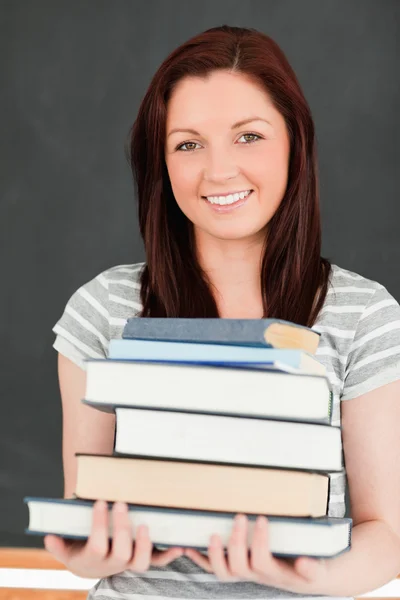 Retrato de uma ruiva sorridente segurando livros — Fotografia de Stock
