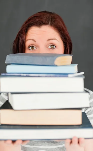 Jonge vrouw hidding achter een stapel boeken — Stockfoto