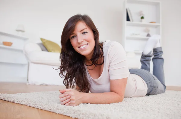 Schöne brünette Frau posiert auf einem Teppich liegend — Stockfoto