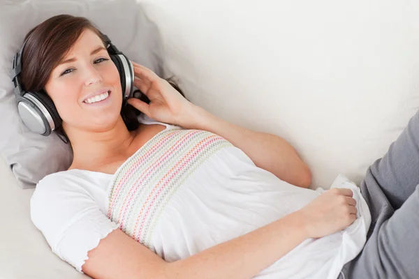 Nádherná bruneta žena relaxační s její sluchátka při ležící — Stock fotografie