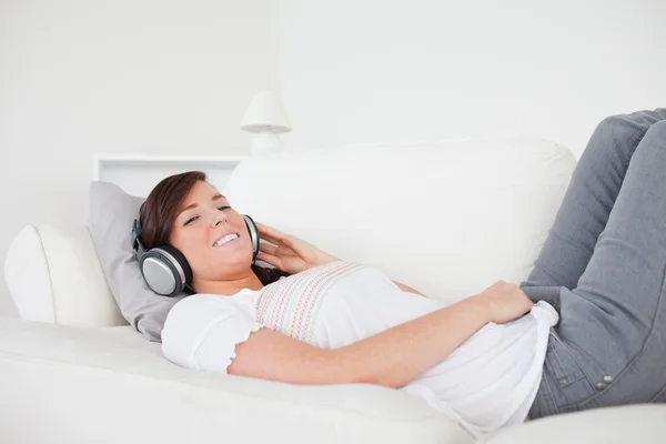 Good looking brunette female relaxing with her headphones while — Stock Photo, Image