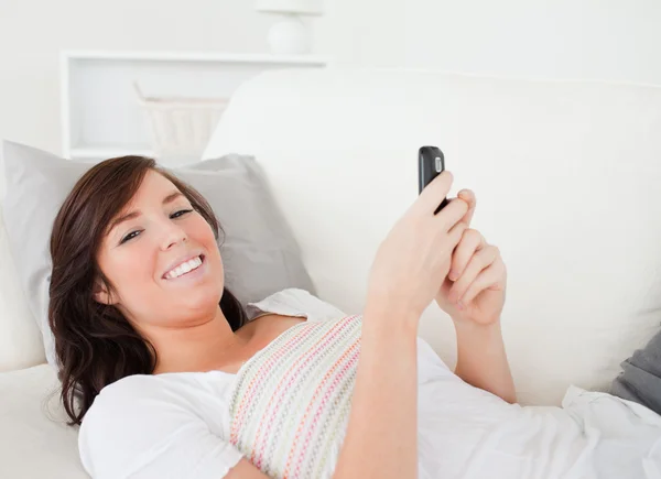 Mulher morena atraente escrevendo um texto em seu celular — Fotografia de Stock