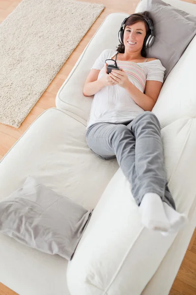ソファの上に横たわっている間電話で良い探しブルネットの女性 — ストック写真