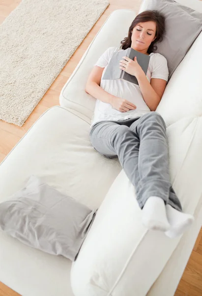 Jovem bonito feminino tendo um descanso e lendo um livro enquanto deitado o — Fotografia de Stock