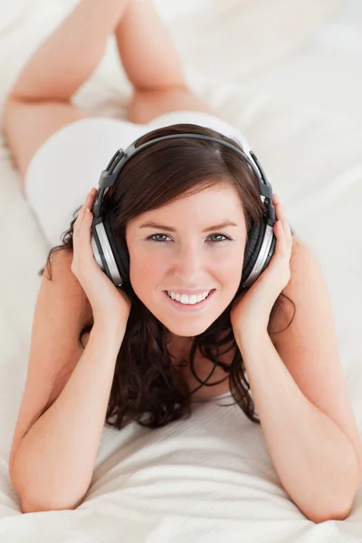 Dobra kobieta szuka ze słuchawkami leżącego — Zdjęcie stockowe