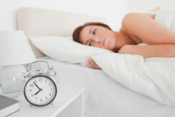Belle femme brune se réveillant avec une horloge tout en étant couché — Photo