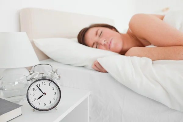 Чарівна брюнетка жінка прокидається з годинником, лежачи — стокове фото