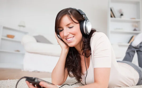 Söt brunett kvinna lyssna på musik med sin mp3 spelare samtidigt — Stockfoto