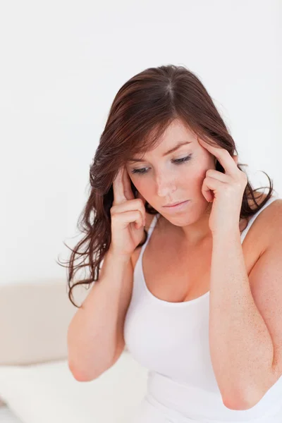 Attraente bruna donna avendo un mal di testa mentre seduto — Foto Stock
