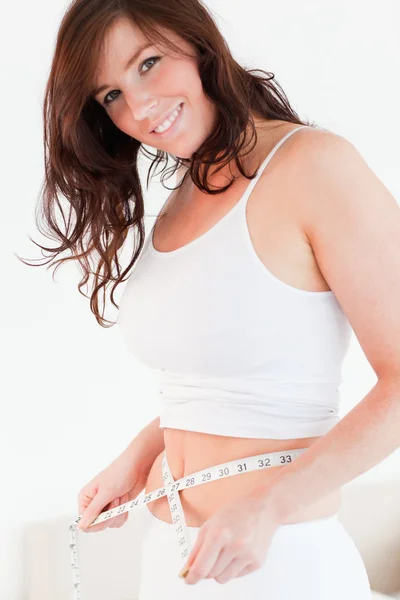 Attractive brunette woman measuring her belly with a tape measur — Stock Photo, Image