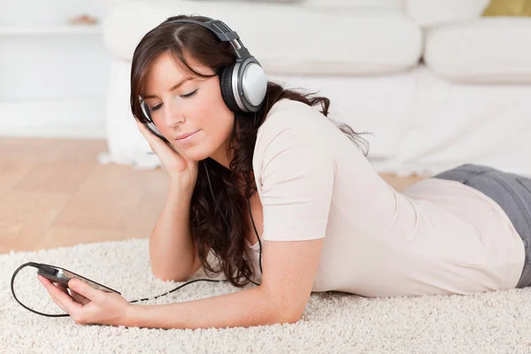 Encantadora morena femenina escuchando música con su reproductor de mp3 —  Fotos de Stock