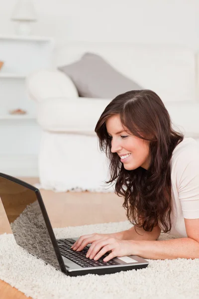 Dobře vypadající bruneta žena pohodové s laptopem vleže — Stock fotografie