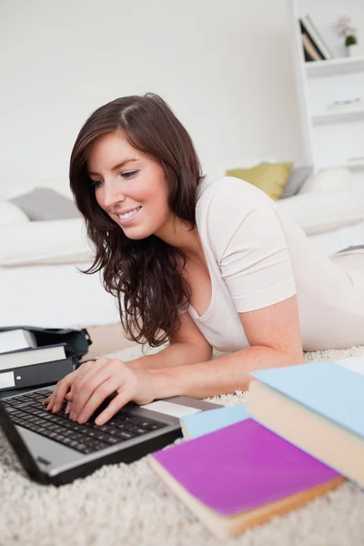 Giovane donna di bell'aspetto rilassante con il suo computer portatile mentre sdraiato su — Foto Stock
