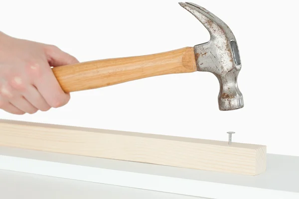 Hammer driving a nail into a wooden board — Stock Photo, Image