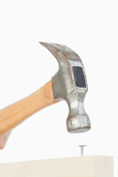 Primo piano di un martello che spinge un chiodo in una tavola di legno — Foto Stock